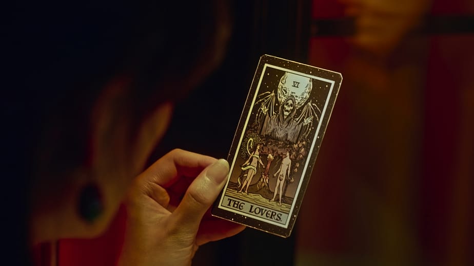"She is So Perfect" movie still featuring the main lead holding a tarot card with the image of death, symbolizing the theme of change and transformation in the film